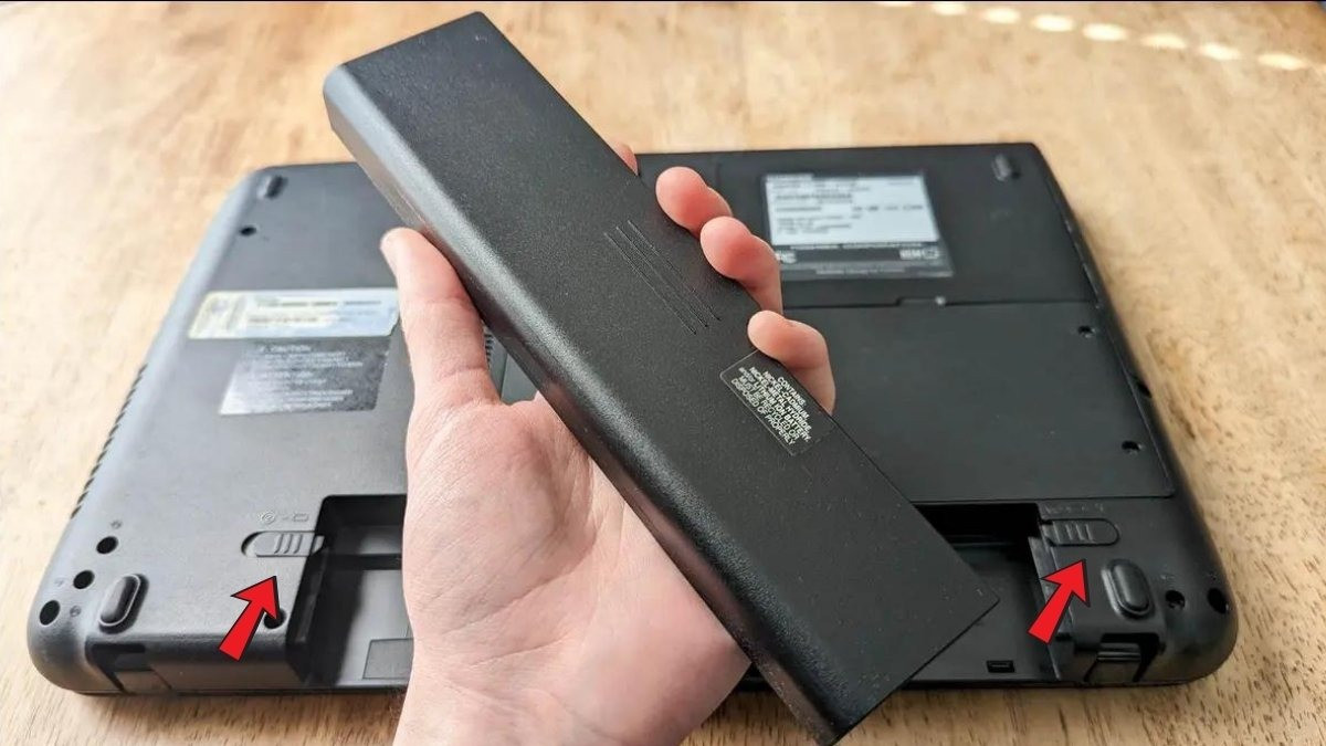 Thao tác đồng thời 2 thanh gạt trên pin rời Dell (2 chốt) trước khi nhấc pin ra